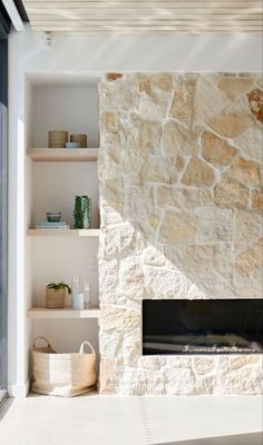 a living room with a stone fireplace and shelves