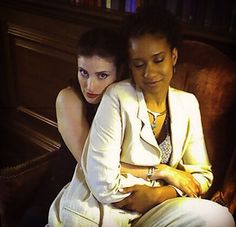 two women sitting next to each other in front of a book shelf