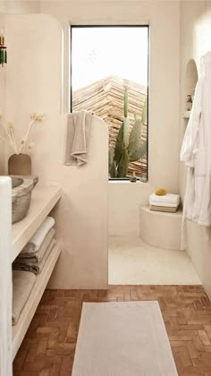 a bathroom with white walls and wooden flooring next to a bathtub filled with towels