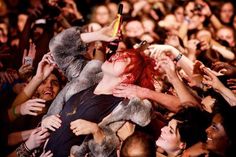 a crowd of people with their hands in the air and one person holding a cell phone