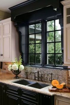 a kitchen with marble counter tops and black framed windows over the sink, along with white cabinets