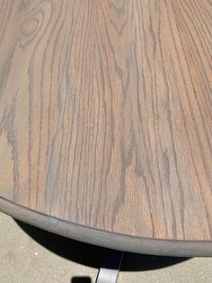 a close up view of a wooden table with metal legs and an oval shaped top