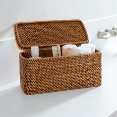 an open wicker basket sitting on top of a white counter next to a faucet