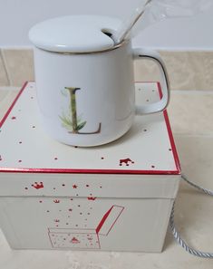 a white coffee cup sitting on top of a box with a spoon sticking out of it