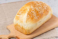 a loaf of bread sitting on top of a cutting board next to a wooden spoon