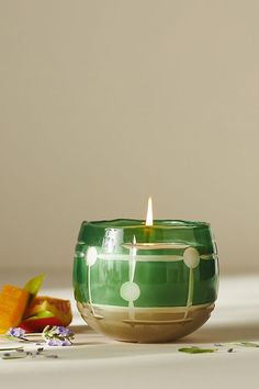 a green candle sitting on top of a table next to an apple and carrot slice