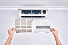 a person is holding up some paint samples to the air conditioner in front of them