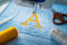 scissors and thread are sitting on a blue towel with the letters a - z in it