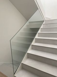 a glass stair case next to a white wall