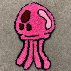 a pink octopus rug on the floor with eyes and lips drawn on it's face