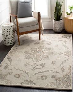 a living room area with a chair, rug and potted plant in the corner