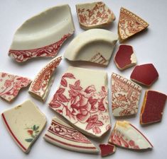 several pieces of pottery sitting on top of a white tablecloth covered surface with red and white designs