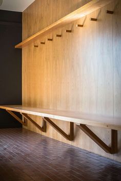 an empty room with wooden shelves on the wall and brick flooring in front of it