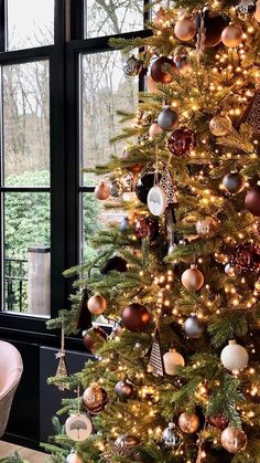 a decorated christmas tree in front of a large window with lots of ornaments on it