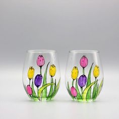 two hand painted wine glasses with flowers on the bottom and green stems in between them