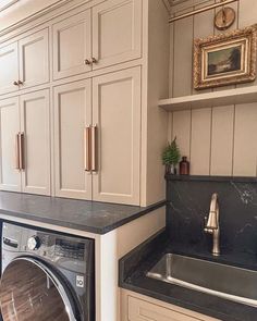 a washer and dryer in a room with white cabinets, black counter tops