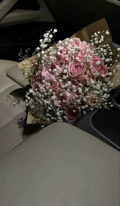 a bouquet of pink roses sitting on top of a car dashboard