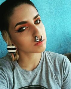 a woman with black and white nose piercings on her nose is looking at the camera