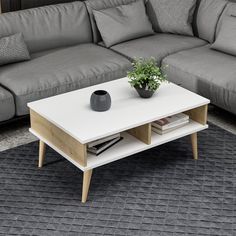 a white coffee table sitting on top of a rug in front of a gray couch