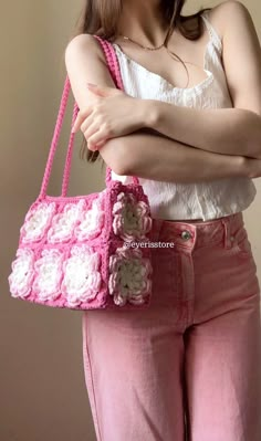 a woman is holding a pink crocheted purse