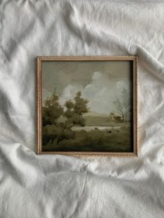 an old painting is hanging on a white bed sheet that has been made into a blanket