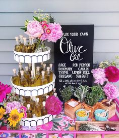 a table topped with lots of bottles and flowers next to a sign that says, use your own olive oil