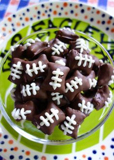 chocolate football candies in a glass bowl on a green and white polka dot plate