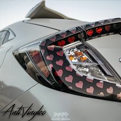 the tail lights of a silver car with hearts on it's grille and hood