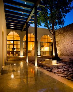 the inside of a house with large windows and lights on it's sides, at night