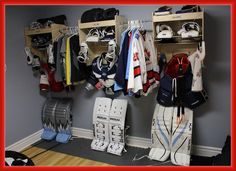 an organized hockey locker with clothes and equipment hanging on the wall next to each other