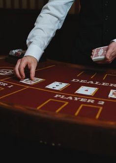 a man in a vest is playing cards at a blackjack table with dices