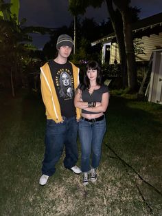 a man and woman standing next to each other in front of a house at night