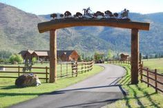 an open gate leading to a farm with animals on it and mountains in the background