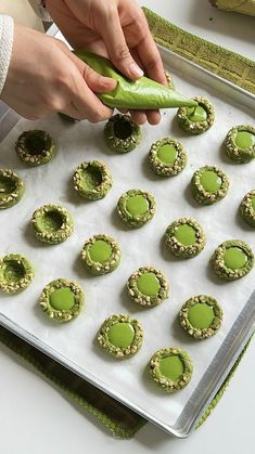 a person is decorating cookies with green icing