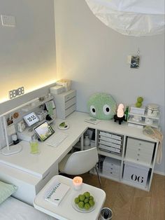 a white desk topped with a laptop computer next to a green stuffed animal on top of it