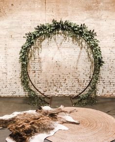 an animal skin rug with greenery on it in front of a brick wall