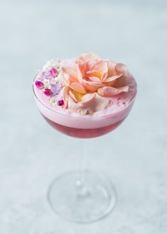 a pink cocktail with flowers on the rim