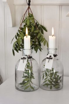 two vases with candles and greenery in them