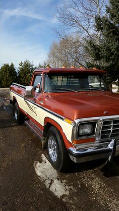 an orange and white truck parked in the dirt