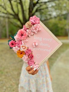 a woman holding a sign with flowers on it that says, long story short forever