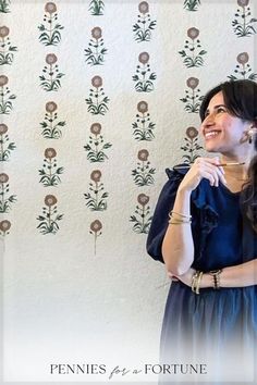 a woman standing in front of a wall with flowers on it