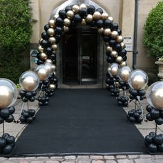 an entrance decorated with balloons and black and gold balls