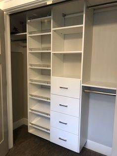 an empty closet with white shelves and drawers