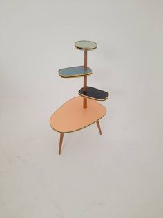 three tiered wooden table with glass top in the shape of a surfboard on it