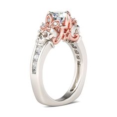 an engagement ring with pink and white diamonds on the side, set in 18k white gold