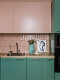 a kitchen with green cabinets and pink backsplash