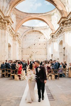 a bride and groom walking down the aisle at their wedding ceremony in an old building