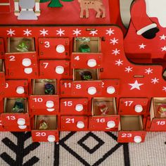 a red wooden christmas tree with lots of ornaments in it and numbers on the side