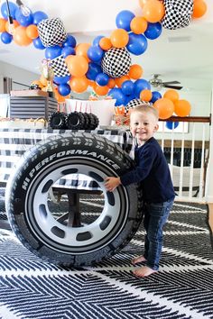 a young boy standing next to a giant tire