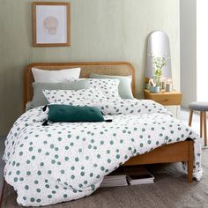 a bed with green and white polka dots on the comforter is in a bedroom